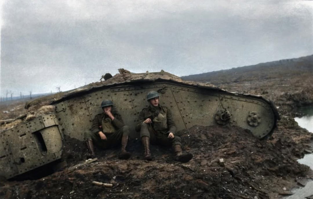 WWI British Tank Wreck in No Man's Land. Two soldiers sit against its side.